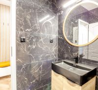 Bathroom in a Holiday Apartment with a black sink and a round mirror.