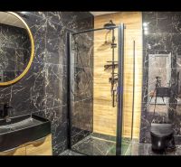Bathroom in a holiday apartment with black tiles and a shower enclosure.