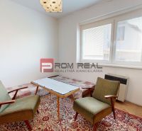A living room in a family house with carpets and wooden furniture, green armchairs.