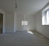 Interior of a family house with white walls, a large window, and a concrete floor.