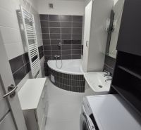 A bathroom with a bathtub, sink, washing machine, and cabinet in a 3-room apartment.