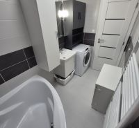 Bathroom with a bathtub, washing machine, and storage cabinets in a 3-room apartment.