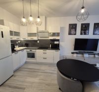 A kitchen unit with a wooden decor floor in a 3-room apartment with stylish lamps.