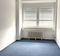 Offices with white walls and blue carpet, illuminated by natural light.