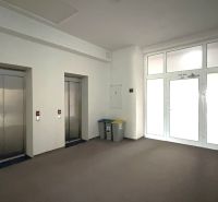 Offices with two elevators and recycling bins, floor with wood decor.