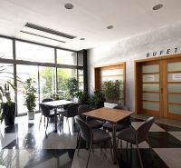 Office interiors with a buffet and glass doors, plants, tables, and chairs.