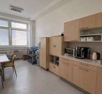 Office interior with kitchenette, table, chairs, and a vending machine.