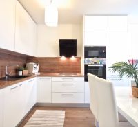 A kitchen in a 2-room apartment with white cabinets and a wood-patterned floor.