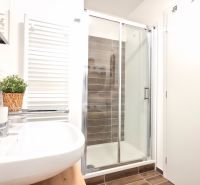 Bathroom with a sink, shower corner, and white radiator in a 2-room apartment.