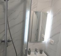 A bathroom in a 3-room apartment with marble tiles and a shower corner.