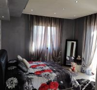 A bedroom in a villa with windows, a mirror, and a bed with a floral pattern.