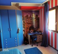 A room in a villa with blue furniture, red stripes, and a poster of a city skyline.