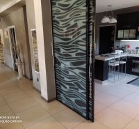 Interior of a villa with glass doors and a kitchen, floor with wood decor.