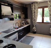 A kitchen in a villa with dark cabinets, a window, and patterned curtains.