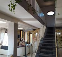 Interior of a villa with a spacious staircase, flowers, and a comfortable living area.