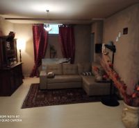 Living room in a villa with a sofa, curtains, decorations, and a wooden-patterned floor.