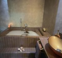 A luxurious bathroom in a villa with a bathtub surrounded by ceramic tiles and accessories.