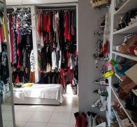Wardrobe in the Villa with a variety of clothes, shoes, and accessories on the shelves.