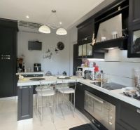 A kitchen in a villa with elegant black cabinets, a bar counter, and modern appliances.