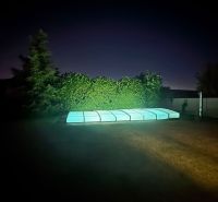 The garden of a family house on Slnečnicová Street in Miloslavov with a lit-up pool at night.