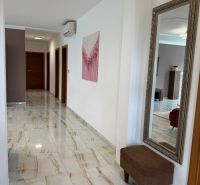 A hallway in a family house with a shiny floor, a large mirror, and wall decorations.