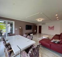 Living room of a family house with a red sofa and a white dining table.