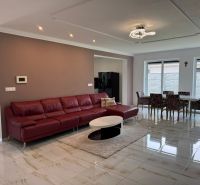 Living room in a family house with a red sofa, dining table, and large windows.