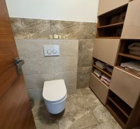 Bathroom in a family house with a toilet, tiles, and storage space for towels.