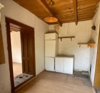 A kitchenette in a cottage with white cabinets and wooden decor on the floor.