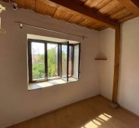 A room with wooden decor, a wooden panel ceiling, and a window with a view of greenery.