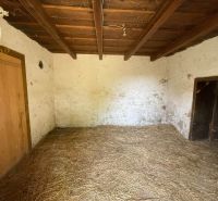 A room with a straw floor and a wooden ceiling in a cabin.