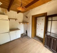 The interior of the cottage with a wood-decorated floor, older furniture, wooden ceiling, glass doors.