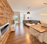 Living room with a brick wall and wood-patterned flooring in a two-room apartment.