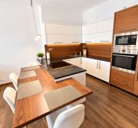 A kitchen in a 2-room apartment with wooden decor and white furniture.