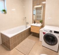 Bathroom with a bathtub, washing machine, and sink in a 2-room apartment.