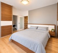 A bedroom in a 2-room apartment with a wood-patterned floor and built-in wardrobes.