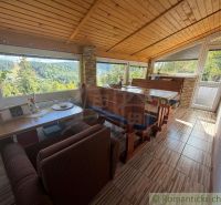 Dining corner in a cottage with a view of green hills and forests.