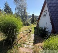 A cottage in Látky with wooden stairs and a view of green hills.