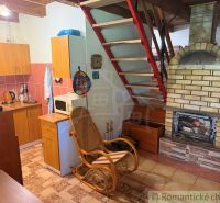 A kitchen corner in a cabin with a fireplace and stairs, floor with wooden decor.