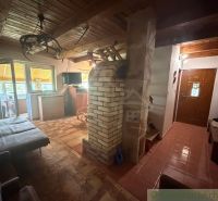 Interior of a cabin with a wooden decor floor, fireplace, and entrance door.