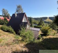 A cottage in Látky surrounded by greenery, with a view of forests and mountains.