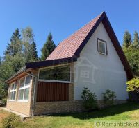 A cottage in Látky, surrounded by greenery and forest, in beautiful sunny weather.