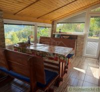 A cottage with a view, wooden furniture, and a floor with a wooden decor, surrounded by nature.