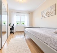 Bedroom in a family house with wood-patterned flooring, a mirrored wardrobe, and a writing desk.