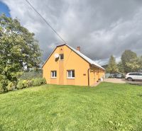 A family house in Oščadnica on Košariská Street with a grassy plot and parked cars.