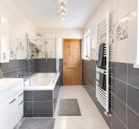 A bathroom in a family house with a bathtub, modern tiles, and wall decorations.