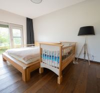 A bedroom with a crib and a large lamp in a 4-room apartment, floor with a wooden decor.