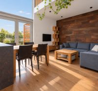 Interior of a 4-room apartment with wood-patterned flooring, a comfortable couch, and a dining table.