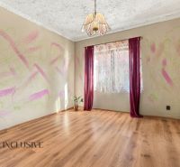 Interior of a family house with a wooden decor floor, colorful wall, and curtains.
