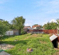 A garden at a family house in Komárno with a lawn and a wooden fence.